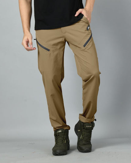 A person wearing desert brown nylon spandex Trekmonk climbing pants with zipped pockets and a pair of boots.