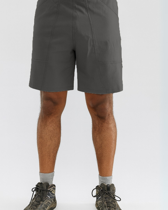 Person wearing gray shorts and hiking boots on a white background