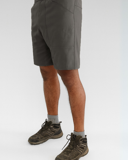 Person wearing dark grey shorts and hiking boots on a white background