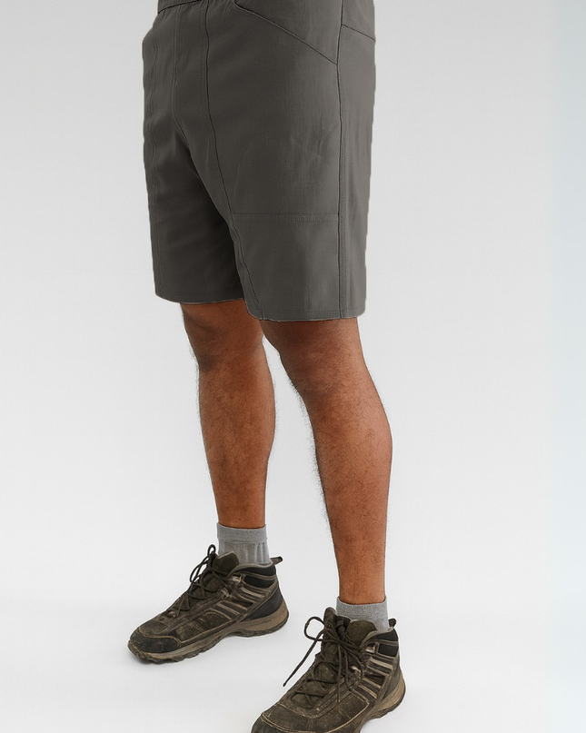 Person wearing dark grey shorts and hiking boots on a white background