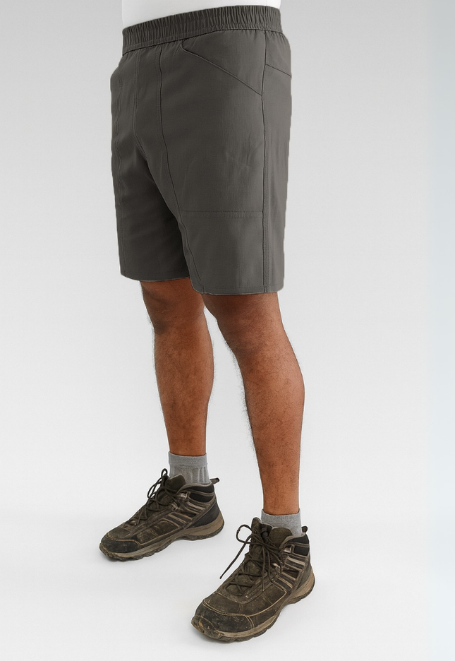 Person wearing dark grey shorts and hiking boots on a white background