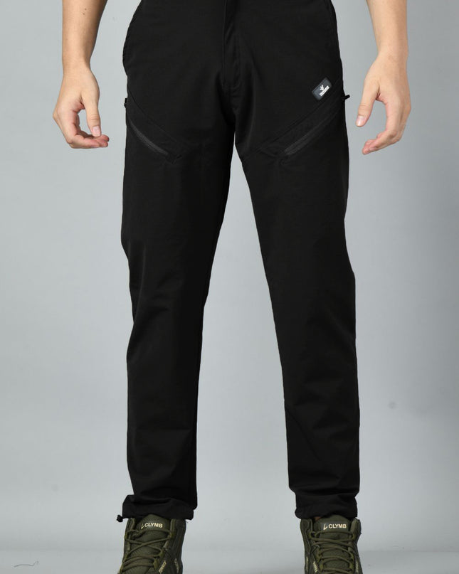 A pair of black nylon spandex trekking pants with reinforced stitching and zipped pockets, paired with hiking boots.