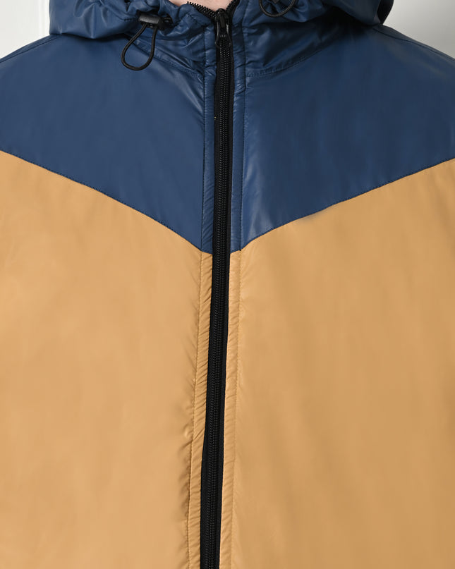 A man wearing a color-blocked windblock jacket with fleece inside mustard yellow and navy blue, with a hood